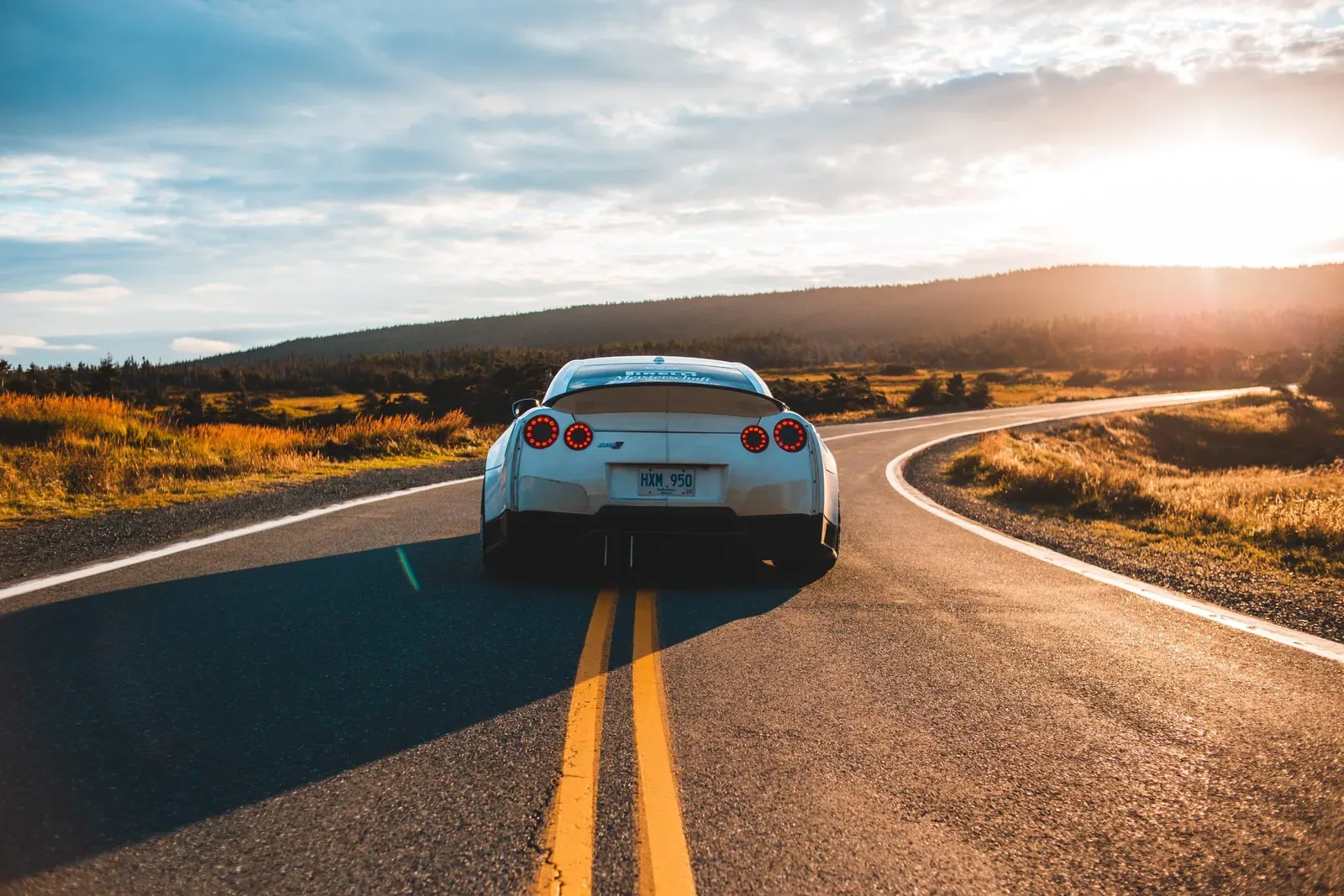 sports car on a two lane highway during sunset