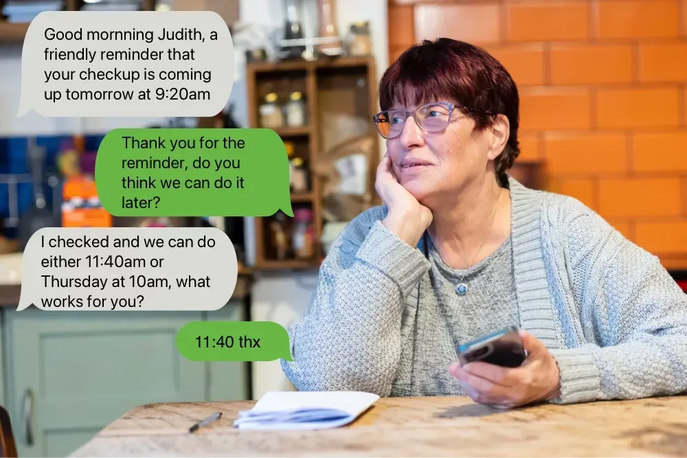 a senior woman sitting at her kitchen table with her mobile phone in one hand